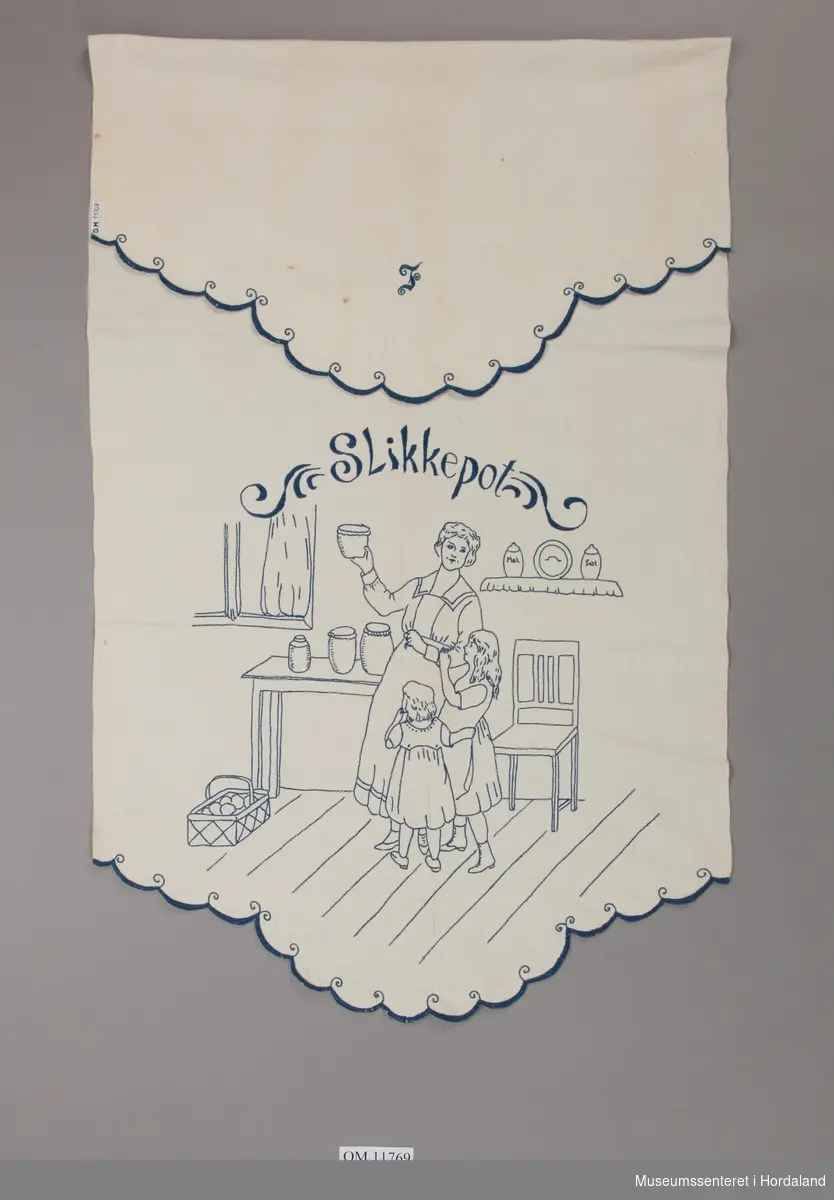 Form: brei, lang, med tungekant i begge ende med motiv av mor på kjøkenet med to jenter, stol, bord, korg, hyller, kar
