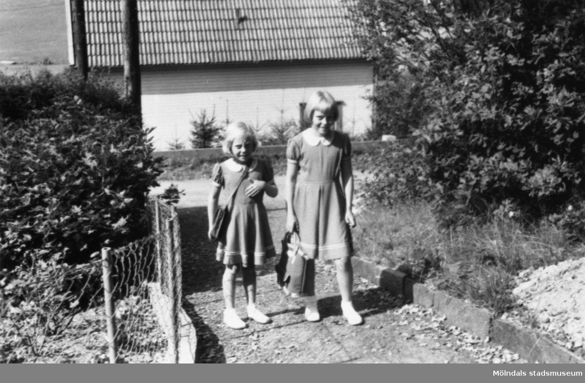 Systrarna Karin (gift: Hansson) och Eva Pettersson (gift: Kempe) på Gamlehagsvägen 17 i Torrekulla, augusti 1954. Det är Karins första skoldag.