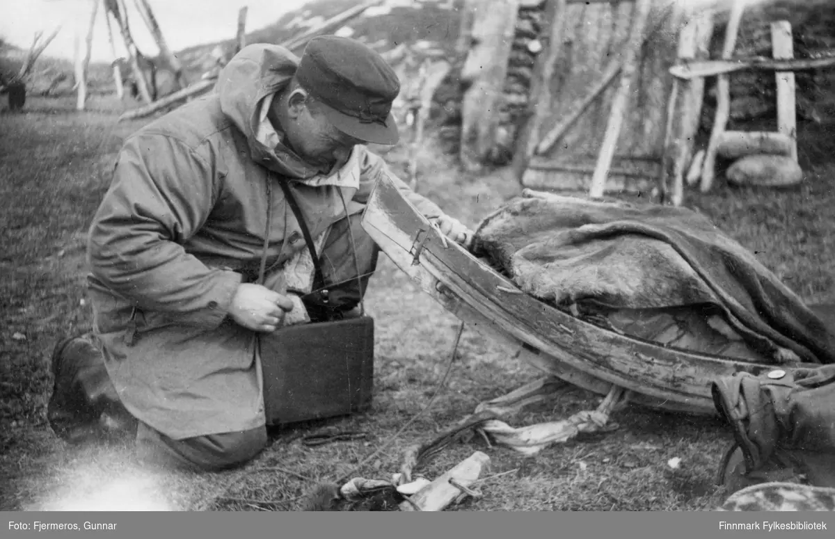 En mann sitter ved siden av en reinslede ved Levajok fjellstue en vårdag i 1948.