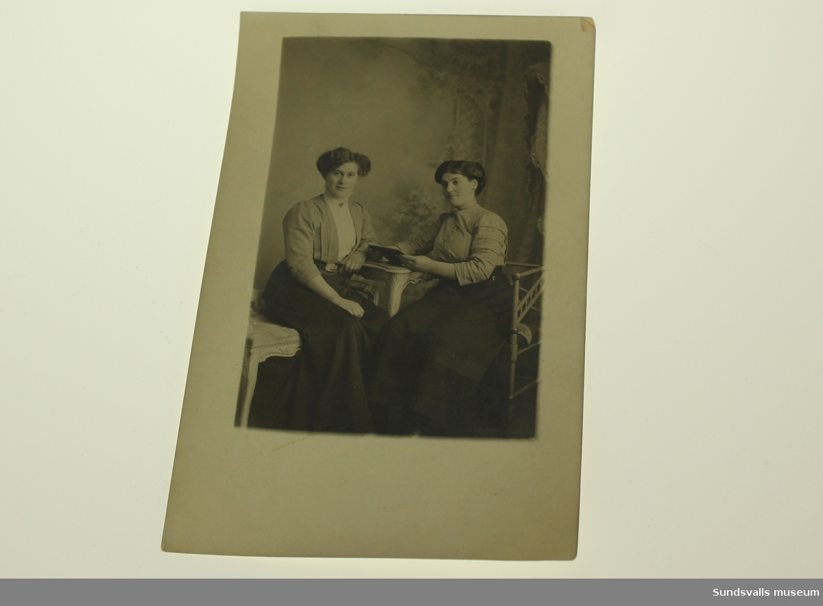 Fotot återger två sittande kvinnor i sekelskiftesklädnad.