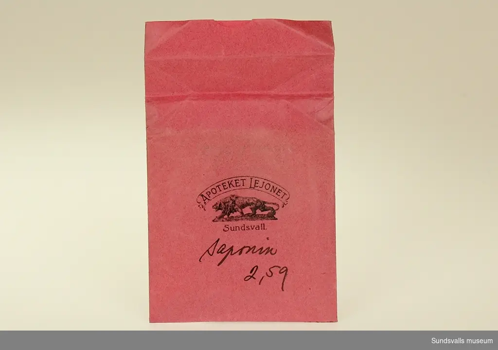 Litet rött kuvert med tryck samt blyertsskrift.		Blyertsskriften uppvisar att innehållet utgörs av saponin 2.59. n. Saponin är ett ämne som ofta används vid rengöring av känsliga material.