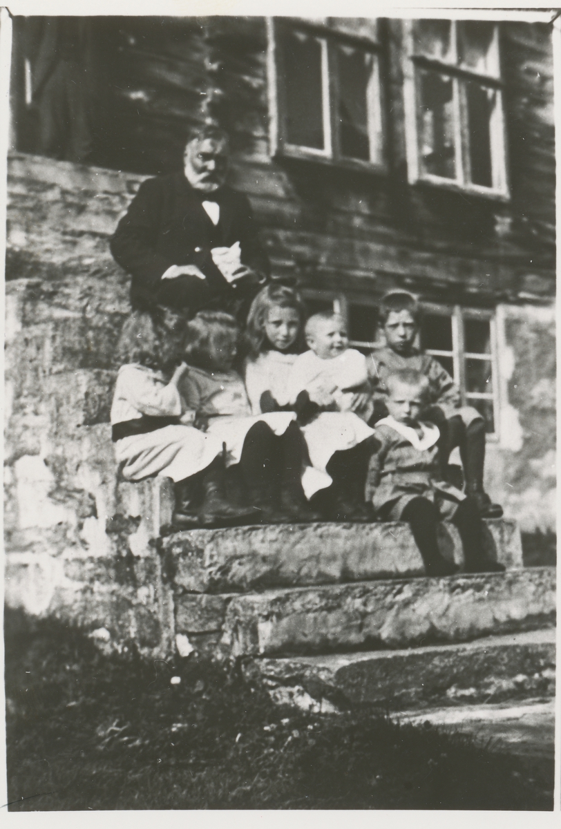 En gruppe barn sammen med Børre Berli på en trapp foran et hus.