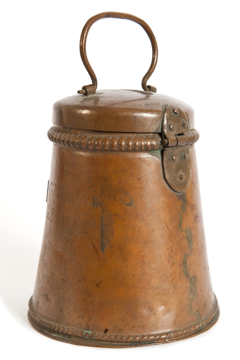 Sparbössa av koppar med hänglås av järn. Inskrift: "Stoftwäfwarnas Fattig Bössa A:W:S:B:I.M.M.D.M.L. Anno 1769."