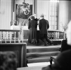 Et brudepar kneler ved alteret, og mottar prestens velsignel