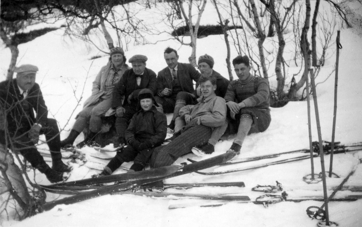 Kvinner og menn på skitur. I midten med sigarett sitter Harry Strand.