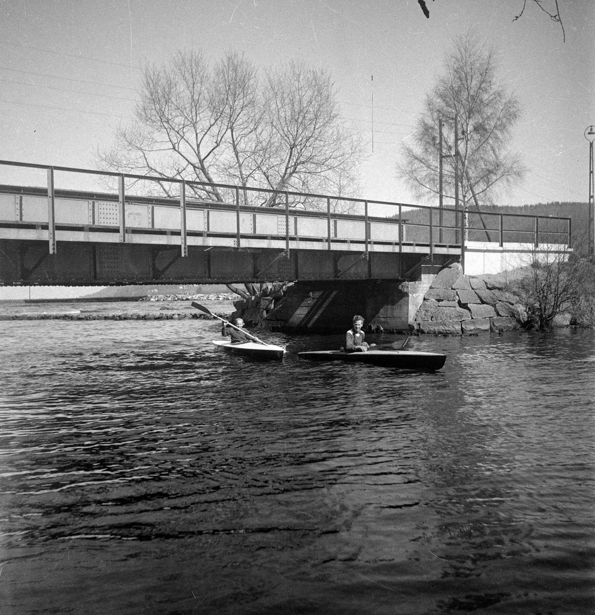 Vid Vättern i Huskvarna paddlar Ove Lind och en pojke sina kanoter under bron.