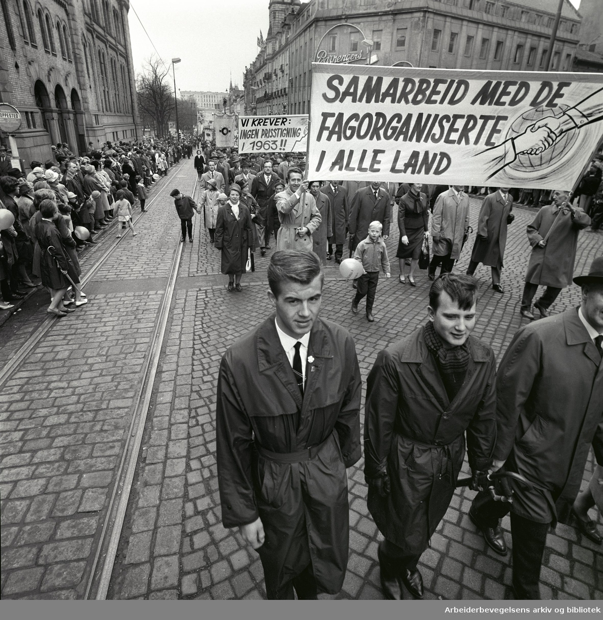 1. mai 1963 i Oslo.Demonstrasjonstoget i Karl Johans gate..Parole : Samarbeid med de fagorganiserte i alle land.Parole : Vi krever: Ingen prisstigning i 1963