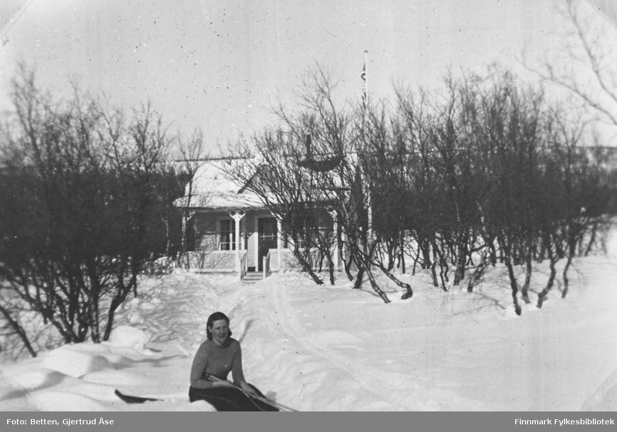 En kvinner, søster Ingeborg Moan, sitter på skiene sine i snøen ved sin hytte i Nyborg. Dagen er solig og vindstille.