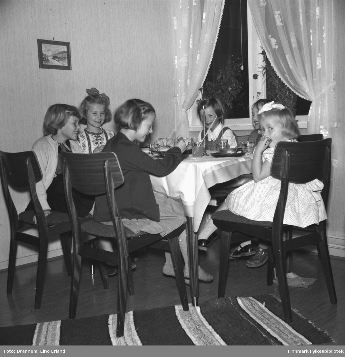 Fem jenter på bursdagsselskap hos Turid Lillian. Jentene sitter ved bordet og drikker saft med sugerør og spiser kaker