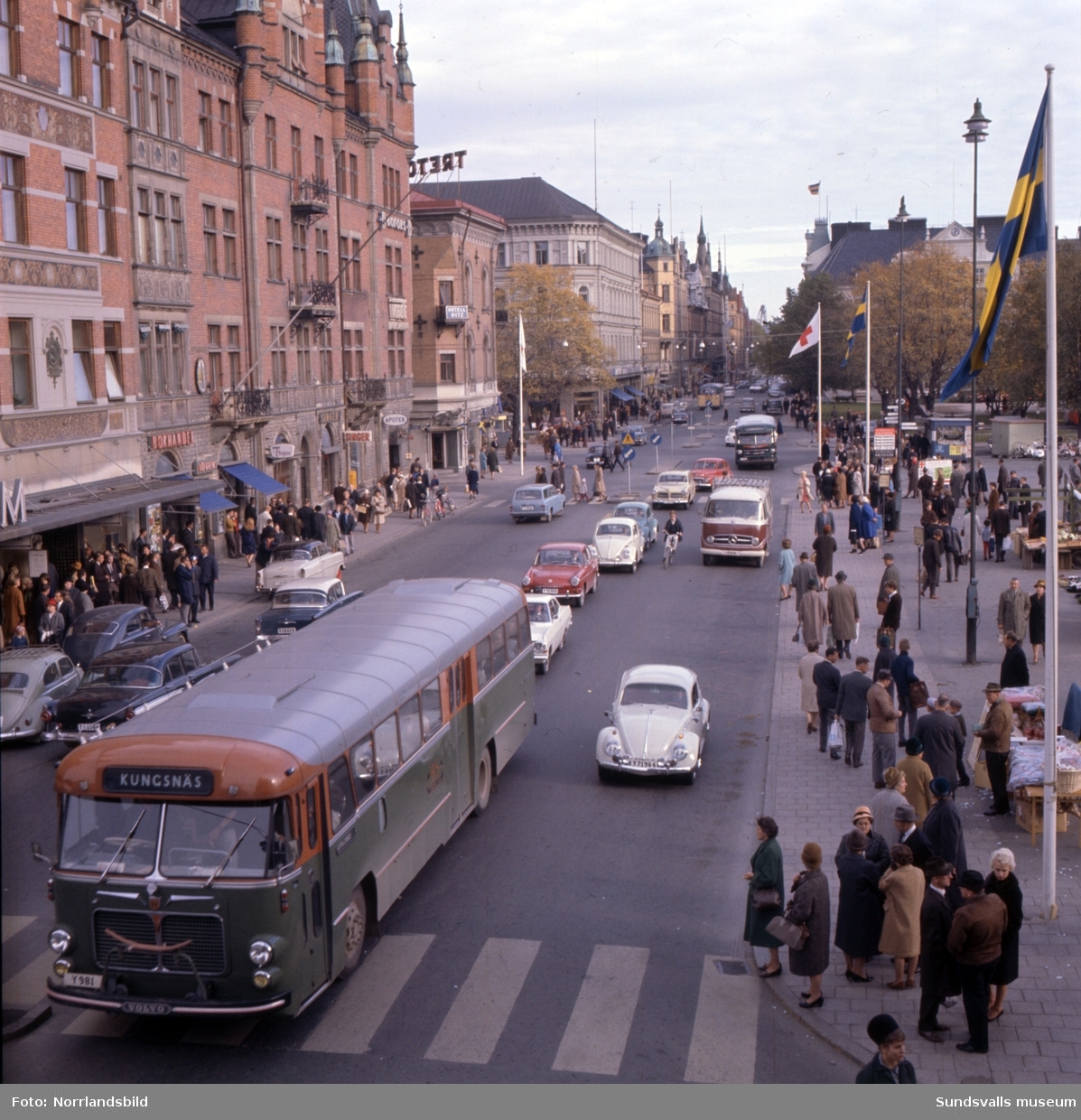 Storgatan vid torget är livligt trafikerad, bussen till Kungsnäs passerar, och folk flanerar på torg och trottoarer. Bilderna är tagna från Torggatan och österut.