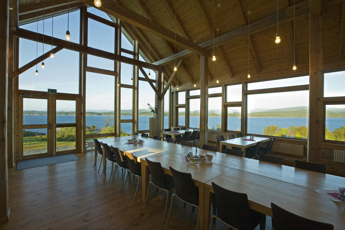 Interiør med langbord, vindauge med utsikt over kystlandskap. Foto (Foto/Photo)