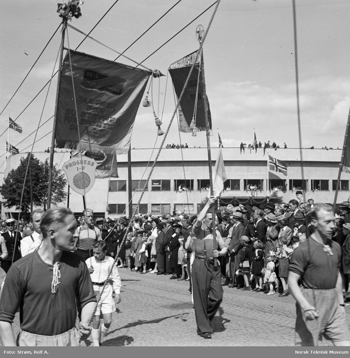 Opptog under Idrettens dag med faner fra Reidulf og Progress idrettsforeninger, utenfor Bislett stadion, Oslo, juni 1945.