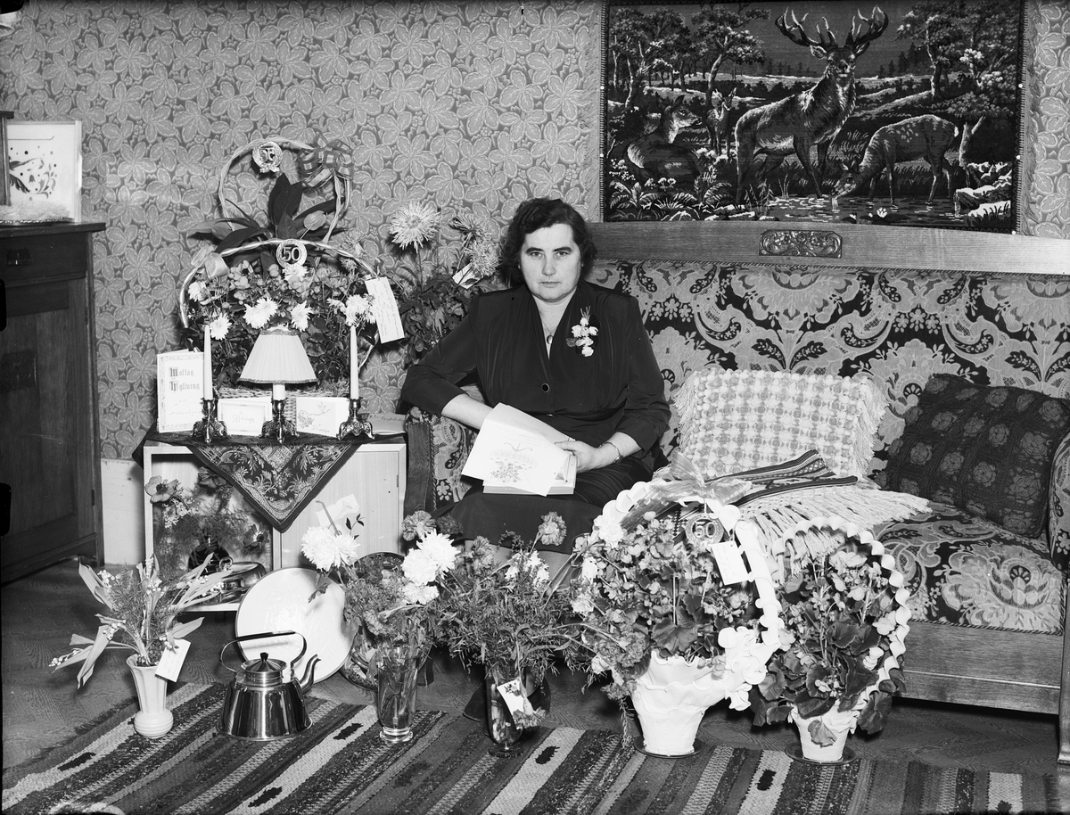 Kvinna i hemmiljö omgiven av blommor, firar 50-årsdag, Östhammar, Uppland