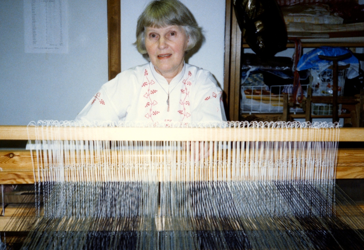 Emy Johansson arbetar hemma i sitt kök med väven till Kållereds Hembygdsdräkts sjal, Torrekulla 1980-tal. Relaterade motiv: A2911-A2916.