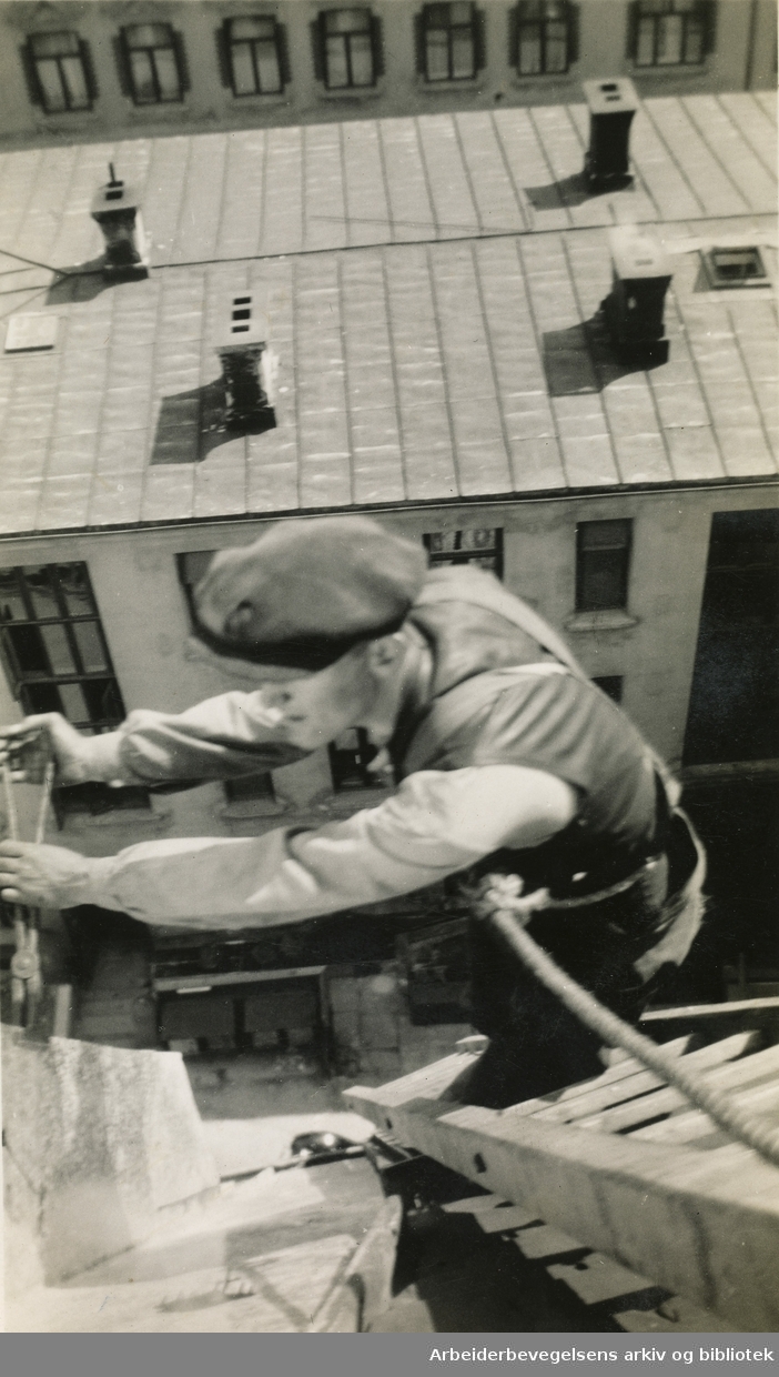 En blikkenslager utfører takarbeide på en bygård i Hegdehaugsveien 27, 1933.