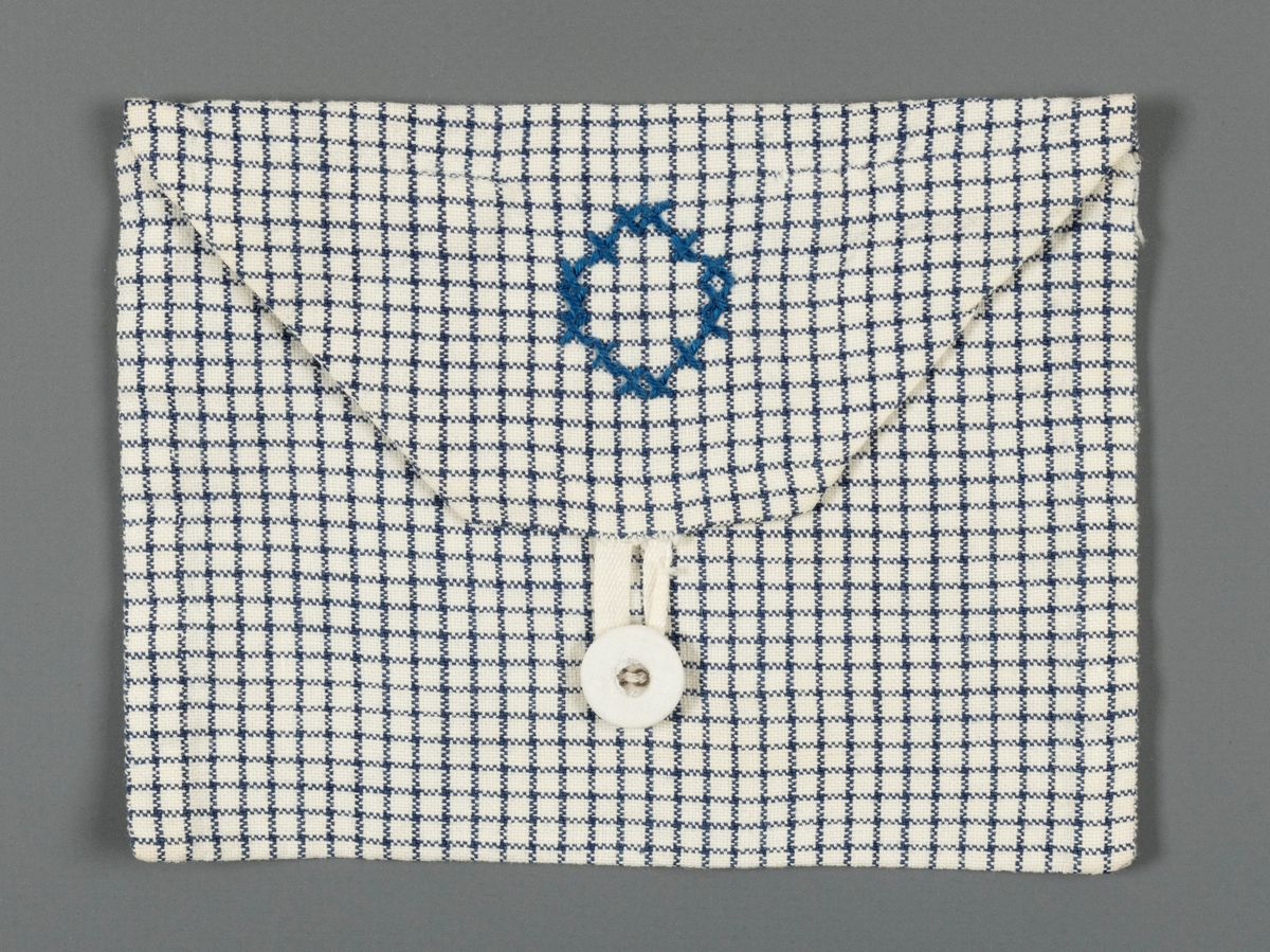 Firkantet stoffmappe, liten, kanskje til lommetørklær. Blårutet stoff og dekorert med bokstaven "O" i blå korssting foran. Hempe og stofftrukket knapp.