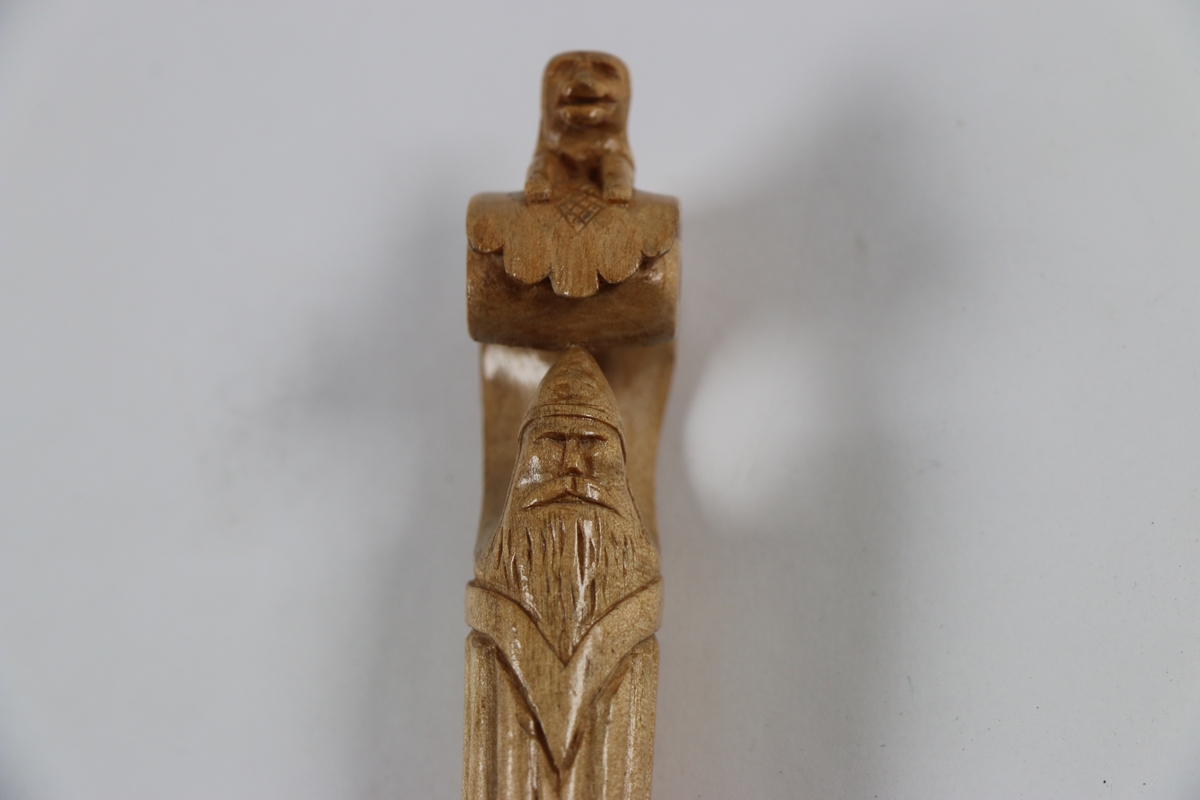 Pent utskåret slire og knivhåndtak med løve og mannsansikt ( med skjegg og "hjelm" ) på håndtaket. 
Motivet av mannen kan minne om en Viking