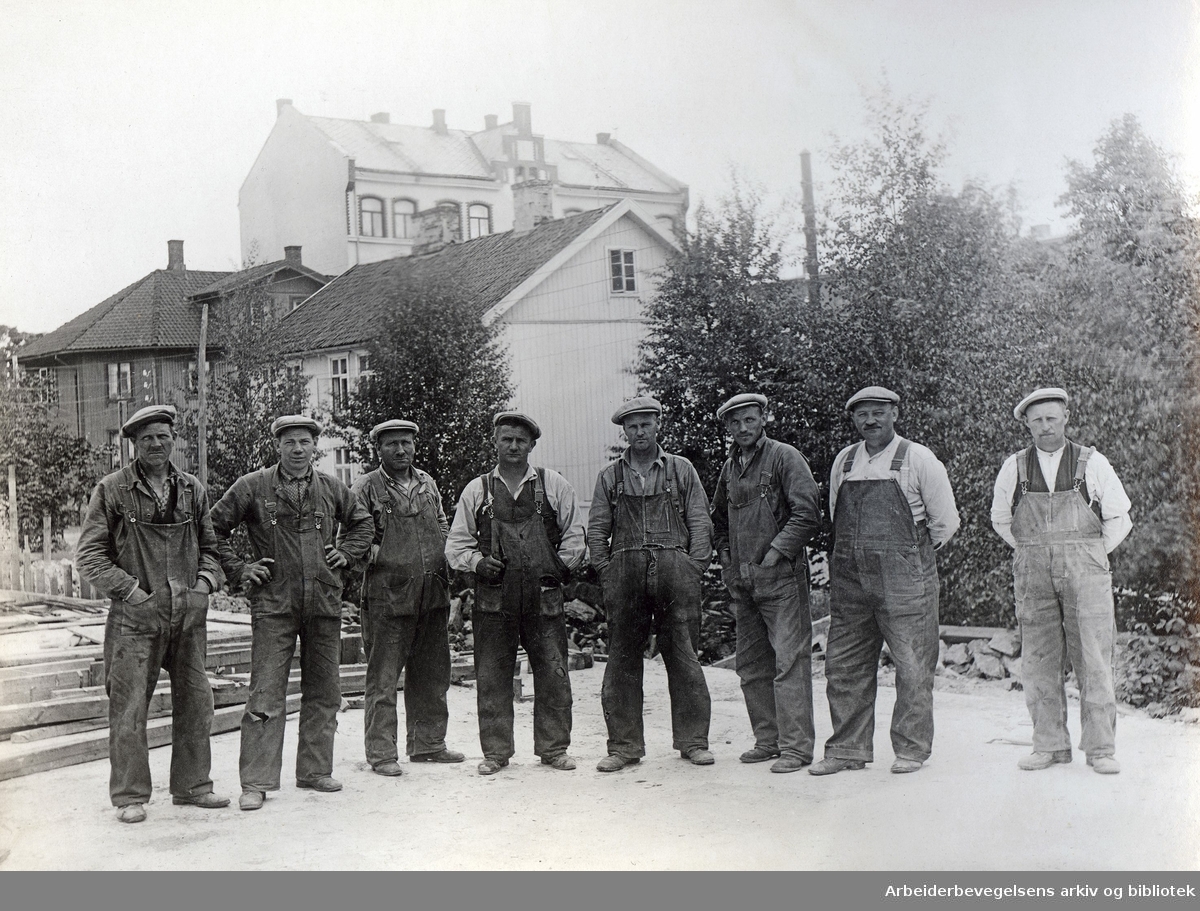 Bygningsarbeidere fotografert i Åsengata på Sandaker i Oslo. Fra høyre; Olaf Nilsen, Haraldsen, ukjent, Kitil Kitelsen, Normann Madsen, Karl Båt, Arthur Olsen og Harald Andersen.