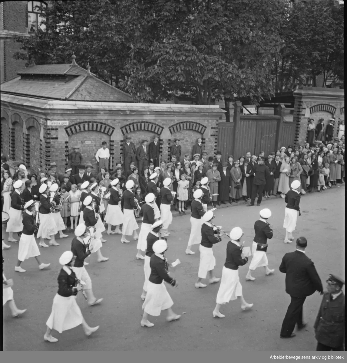 1. Mai 1932. Bildet er tatt på hjørnet av Falsens gate og Nissens gate med Grünerløkka skole i bakgrunnen. Musikkorps. Hornorkester.