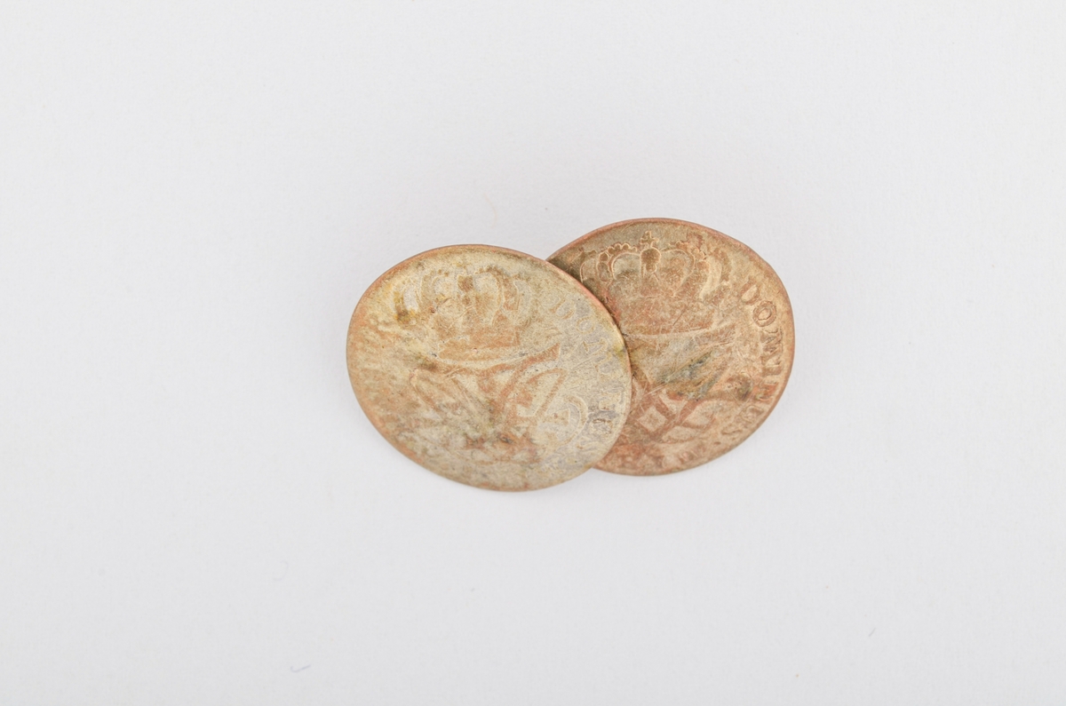 Sølje, halsknapp i sølv. Sett saman av to knappar i ei åttetallsforma hempe i messing. Knappane er gamle myntar frå 1727 og 1728, og som er laga om til knappar. (sjå nærmare registrering på arkivkort 7145).