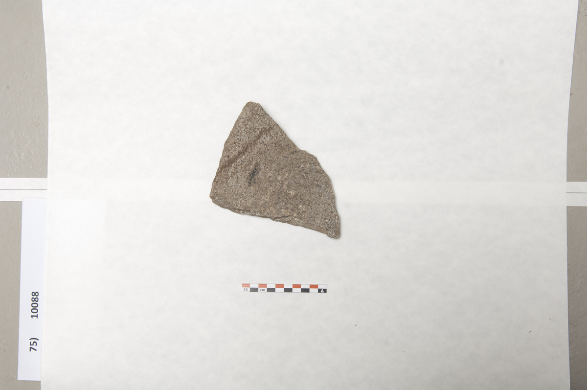 Fragment fra kanten av kvernstein av granat glimmergneis (J.S.D.) St.l.155 mm, st. br. 127 mm, st.t.33 mm. (Q49.)
