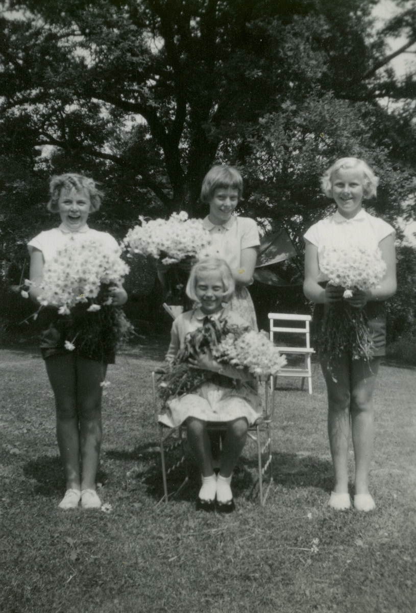 Fyra unga flickor med var sin bukett sitter/står i familjen Hedbergs trädgård i Torrekulla, år 1957. Stående från vänster: Monica Börjesson, Eva Pettersson (född 1944, gift Kempe) och Lena Börjesson. Sittande i mitten: Karin Pettersson (född 1947, gift Hansson). Systrarna var grannar på Gamlehagsvägen i Torrekulla.