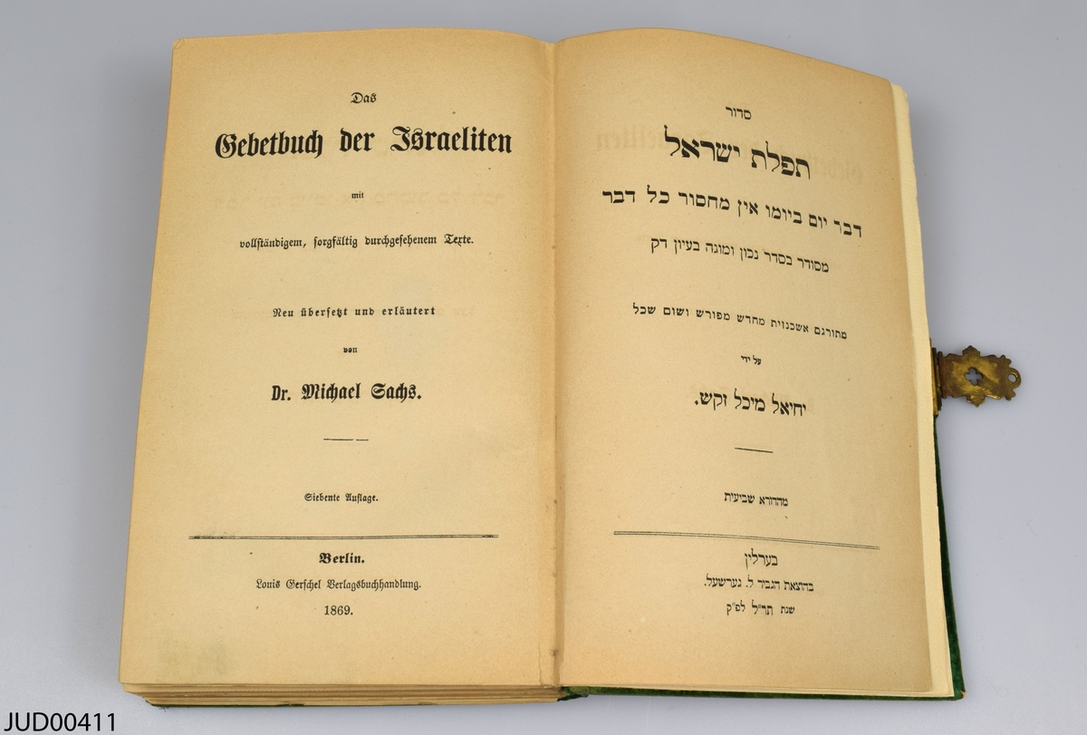 Siddur klädd med grön sammet. Boken är tryckt på papper i Berlin 1869, och är skriven på hebreiska och tyska. Sammeten är dekorerad med en förgylld pressad ram, brodyr gjord med guldtråd (slagmetall) i form av initialerna I [E]W.