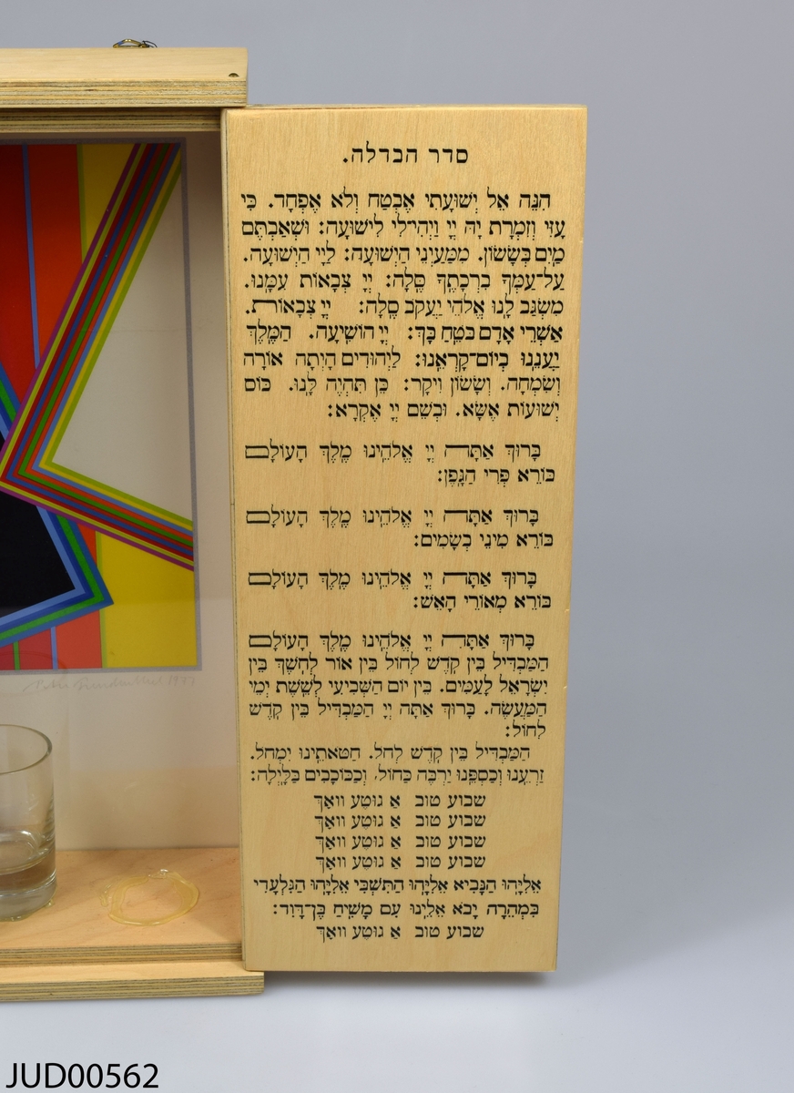 Låda tillverkad av trä för havdala (ceremonin som avsluter judiska sabbaten). Enkel och rak utformning. Öppning framtill med dubbla dörrar dekorerade med varsin davidsstjärna målad i svart. Inuti lådan finns tre små glas, kryddor och havdalaljus. Fonden är dekorerat med abstrakt geometrisk konst signerad Peter Freudenthal. På vänstra dörren dedikationstext på jiddisch, på högra dörren välsignelser för havdalaceremonin på hebreiska. Numrerad 37/77.