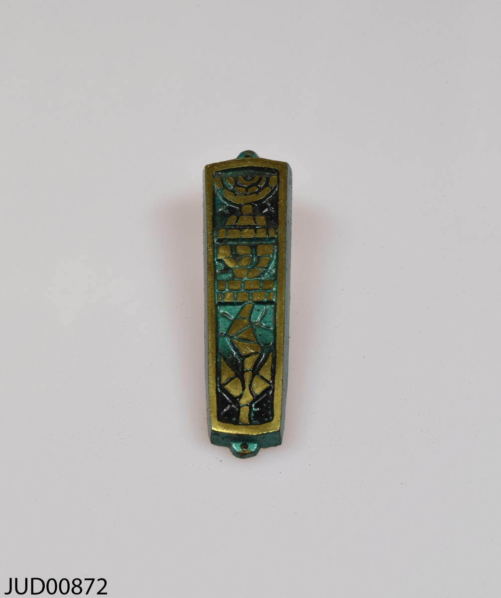 Mezuza tillverkad av metall. Målad grön med guldfärgade detaljer på framsidan.