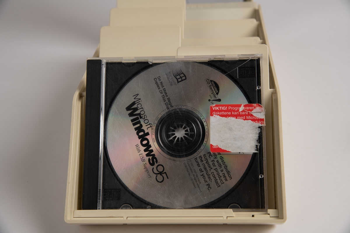 Hvit boks med gjennomsiktig lokk. Inneholder 11 CD-er. CD-ene inneholder ulike programvarer. 
Er også to etuier til CD-plater.