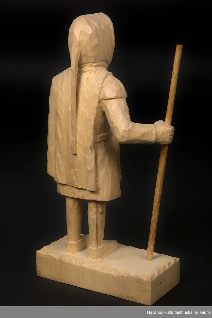 Skulptur av lindträ föreställande Bockstensmannen. Behandlad med klarlack. Signerad "GG" med brännmärkningspenna undertill.
Skulpturen är, utöver vandringsstaven, snidad i ett trästycke.