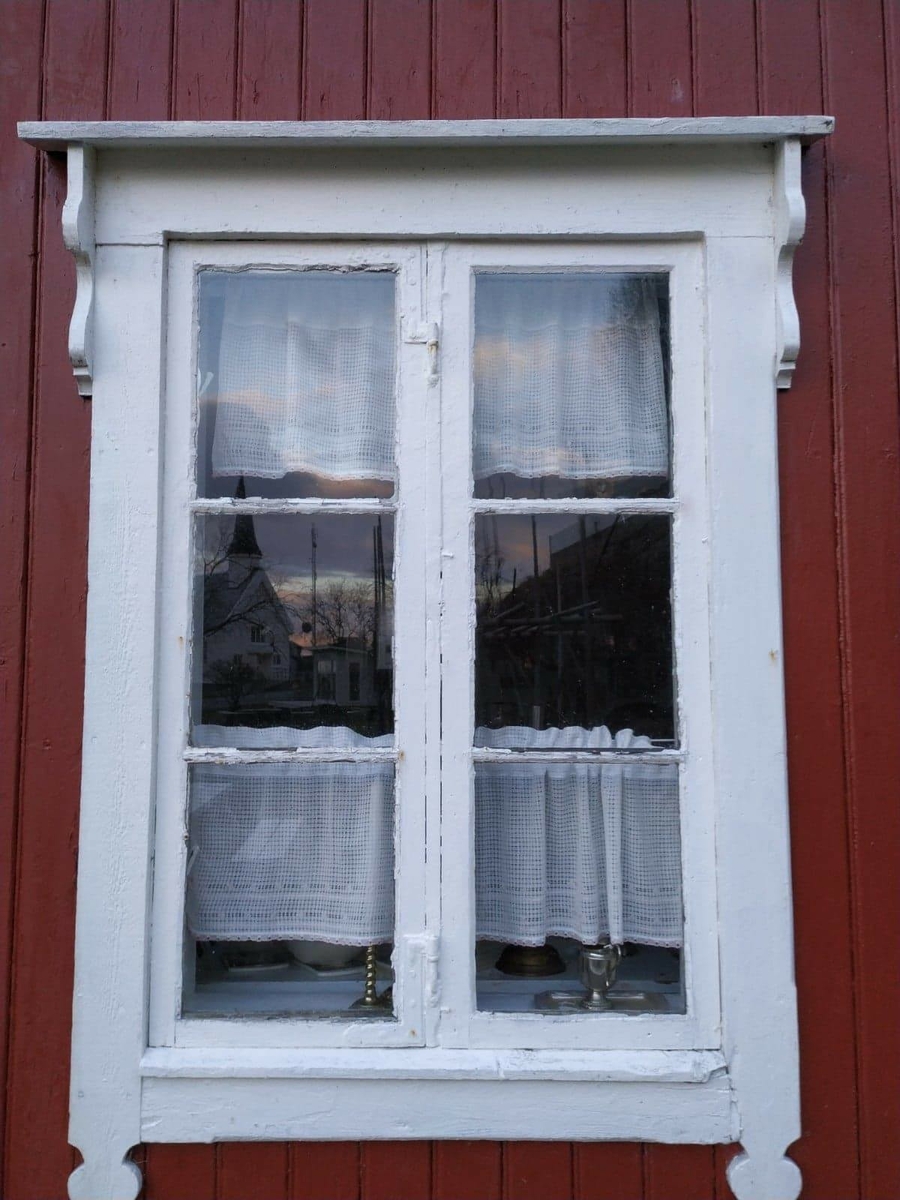 Huset har panel stående panel, malt rødt med hvit dekor på og rundt vinduer. Skifertak.