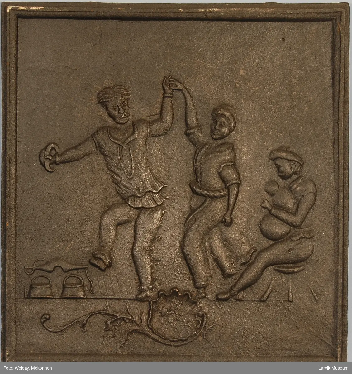 dansende bønder til høyre spillemann med sekkepipe sittende i profil mot venstre på lav krakk til venstre vassele og to trebøtter.