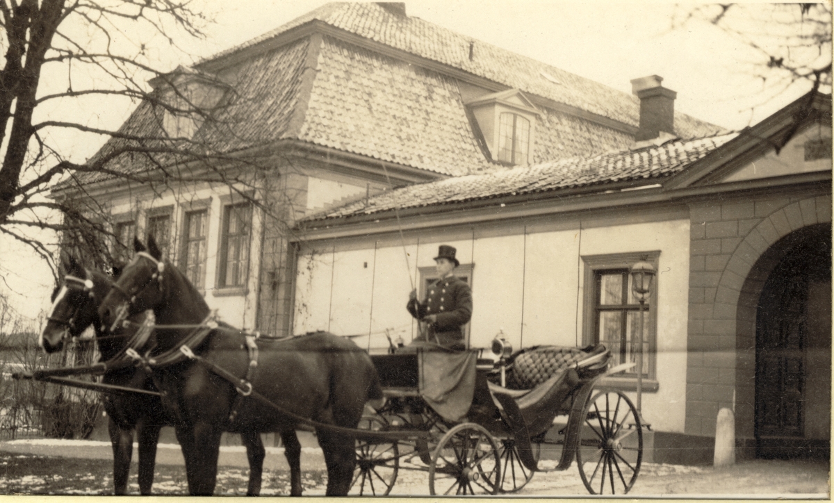 De siste vognhestene på Bogstad gård, "Njaal" og "Capable", er spent for kjøretøyet foran inngangsporten til Bogstad gård. Kusken er Bogstads kusk, Rudolf Persson. Fotografert 1919.