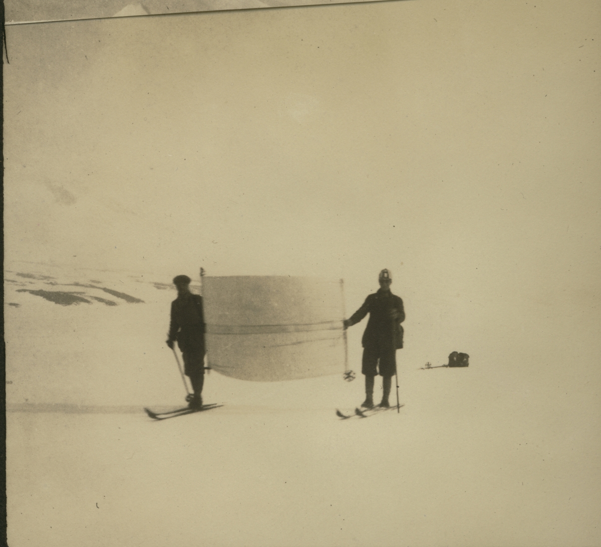 Westye P. Egeberg, E. Damsgaard(?) og Hans Bergsland(?) på skitur over Heggenes, Janin, Olevand,Vinstrer, Bygdisheim, Gjendesheim, Glitterheim og retur. Her bruker to av dem "seil" over Russvatnet. Antagelig fotografert 1921.