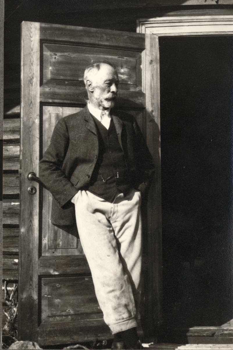 Ferdinand J. Egeberg nyter solen ved stuedøren til hytten Kløfte i Tolga, Hedmark. Fotografert september 1921. Han dør senere etter et fall som utløste et skudd fra hans gevær.