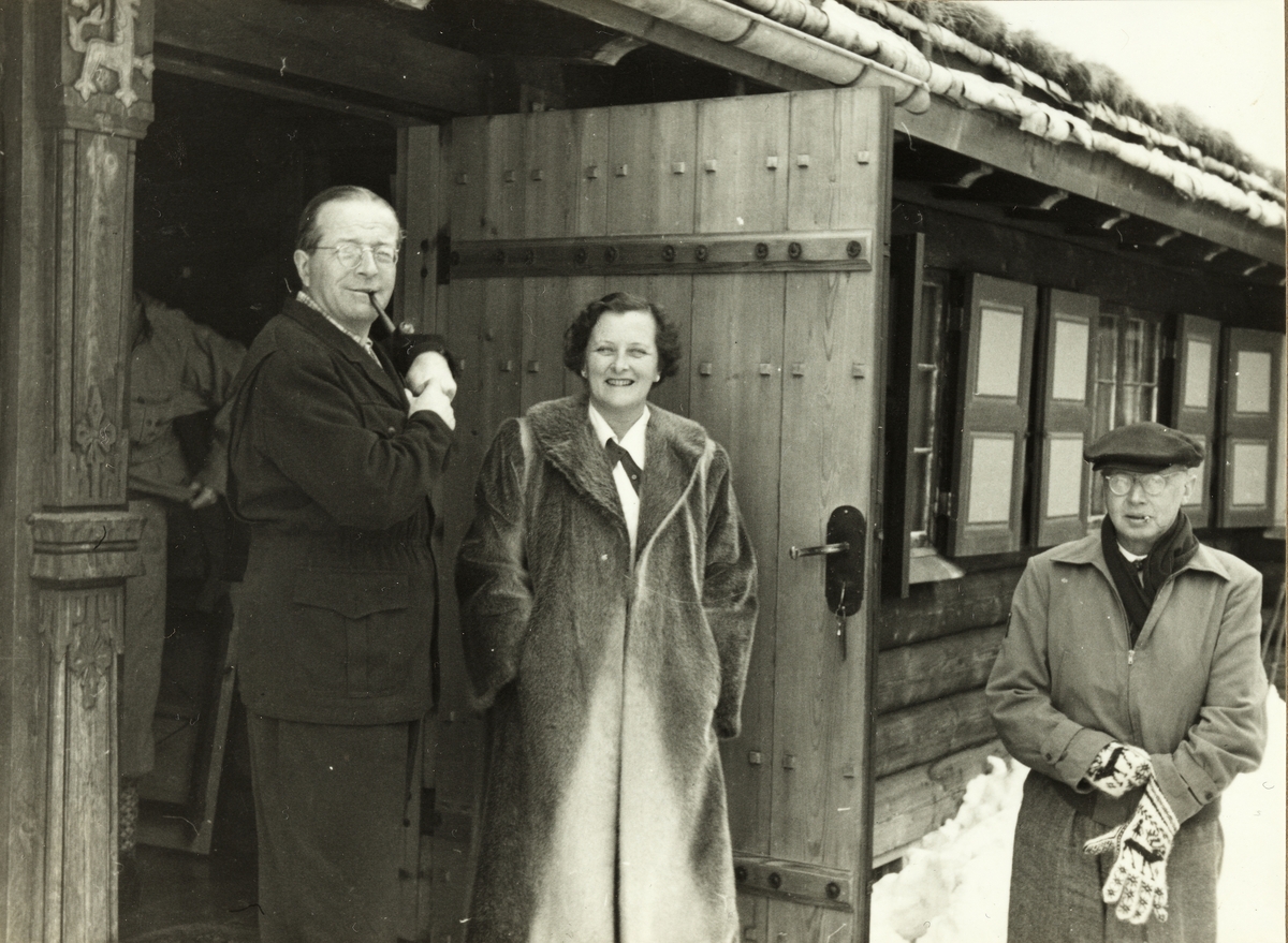 Carl Otto Løvenskiold, Henny Løvenskiold og Sven Adolf Solberg ved inngangen til Carl Otto Løvenskiolds jakthytte ved Sandungen i Nordmarka, Oslo. Fotografert i februar 1953.