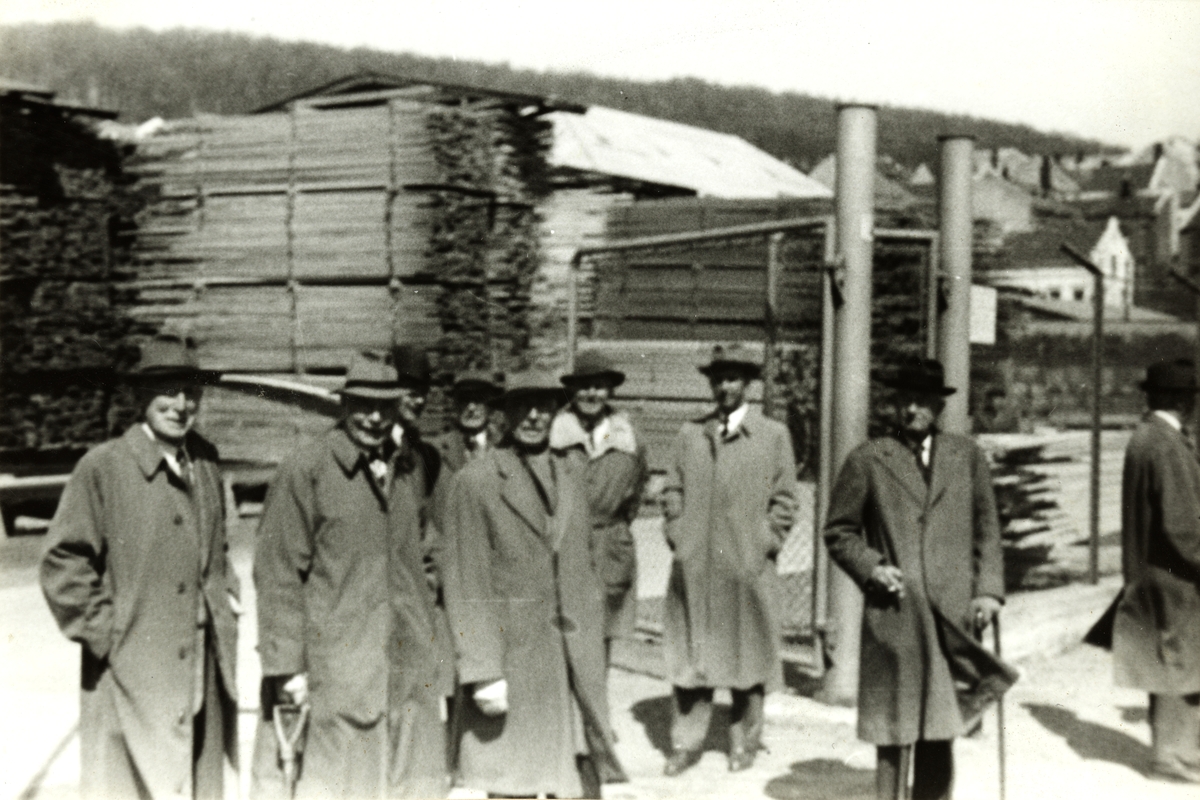 En gruppe, blant dem antagelig Nils O.Y. Fearnley og Carl Rustad, på befaring ved trelastproduksjon på ukjent sted. Fotografert 1956.