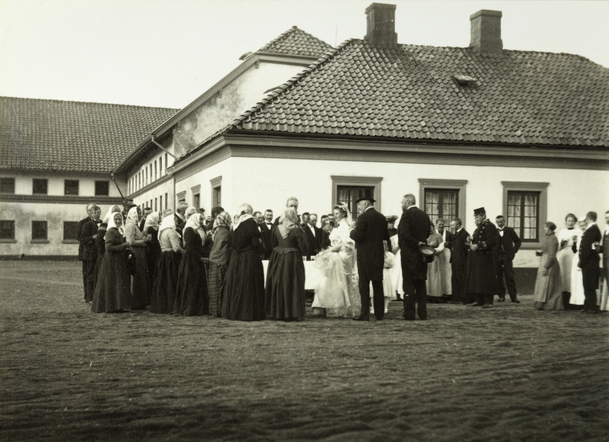 Brudeparet Nini, f. Wedel Jarlsberg, og Westye Parr Egeberg møter de ansatte på gårdsplassen til Bogstad gård. Til høyre for brudeparet står brudens far og eier av Bogstad gård, Herman Wedel Jarlsberg og noen av bryllupsgjestene. Fotografert 17. september 1904.