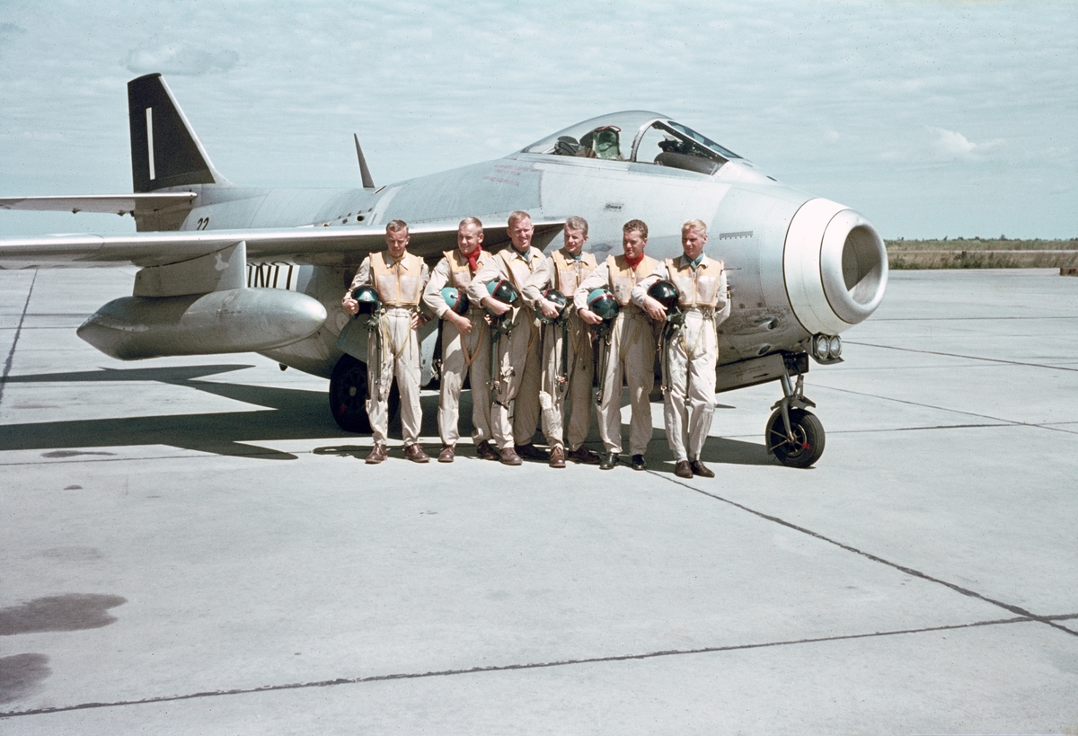 Grupporträtt av svenska FN-piloter i Kongo under 1962-1963 ståendes framför flygplan Saab 29 Tunnan på flygbasen i Kamina.