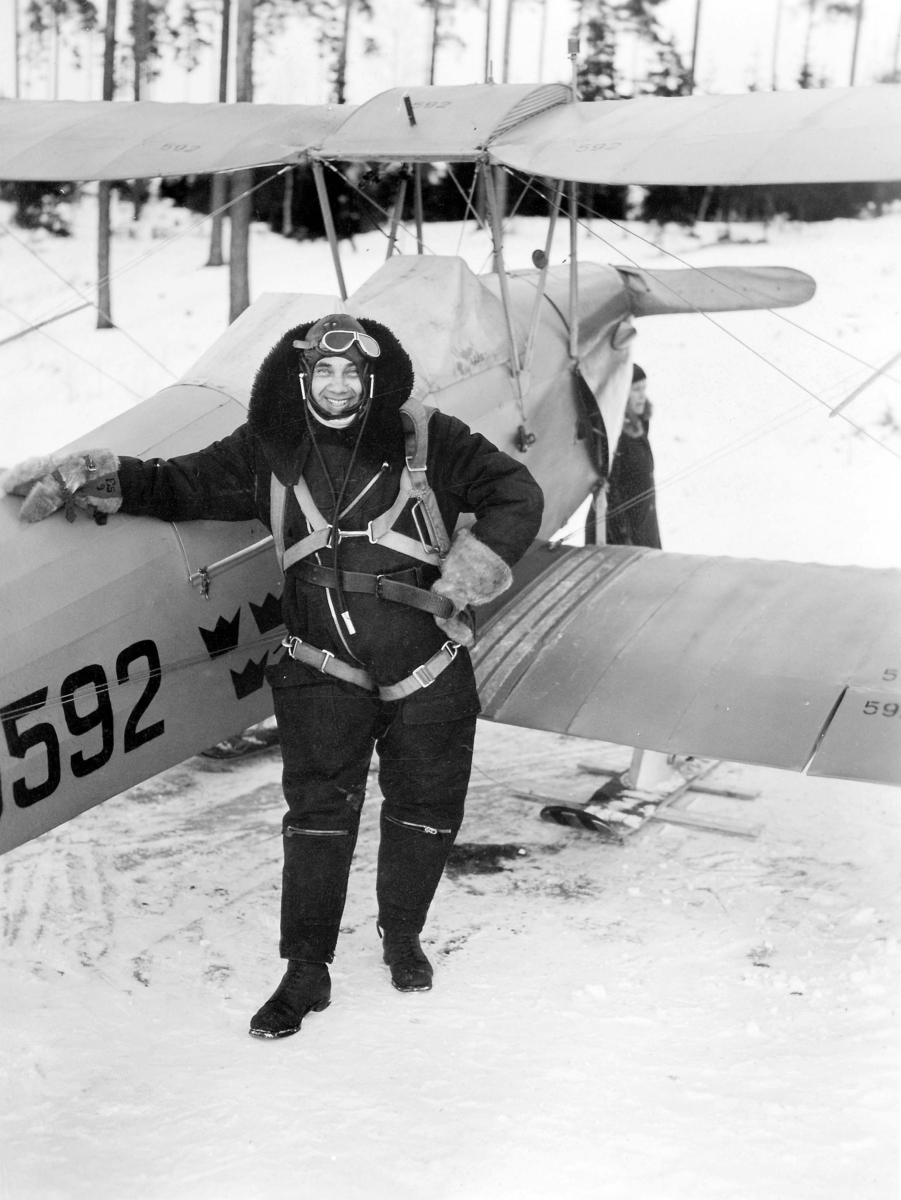 Porträtt av en militär flygare vid flygplan Sk 11, Tiger Moth nummer 5592, vintertid. Cirka 1932-1939.