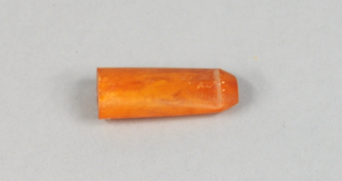 Ovalt, sylinderformet pipemunnstykke av rav, som er smalere i den ene enden. Den smale enden er svakt bøyd og har en kant ytterst.