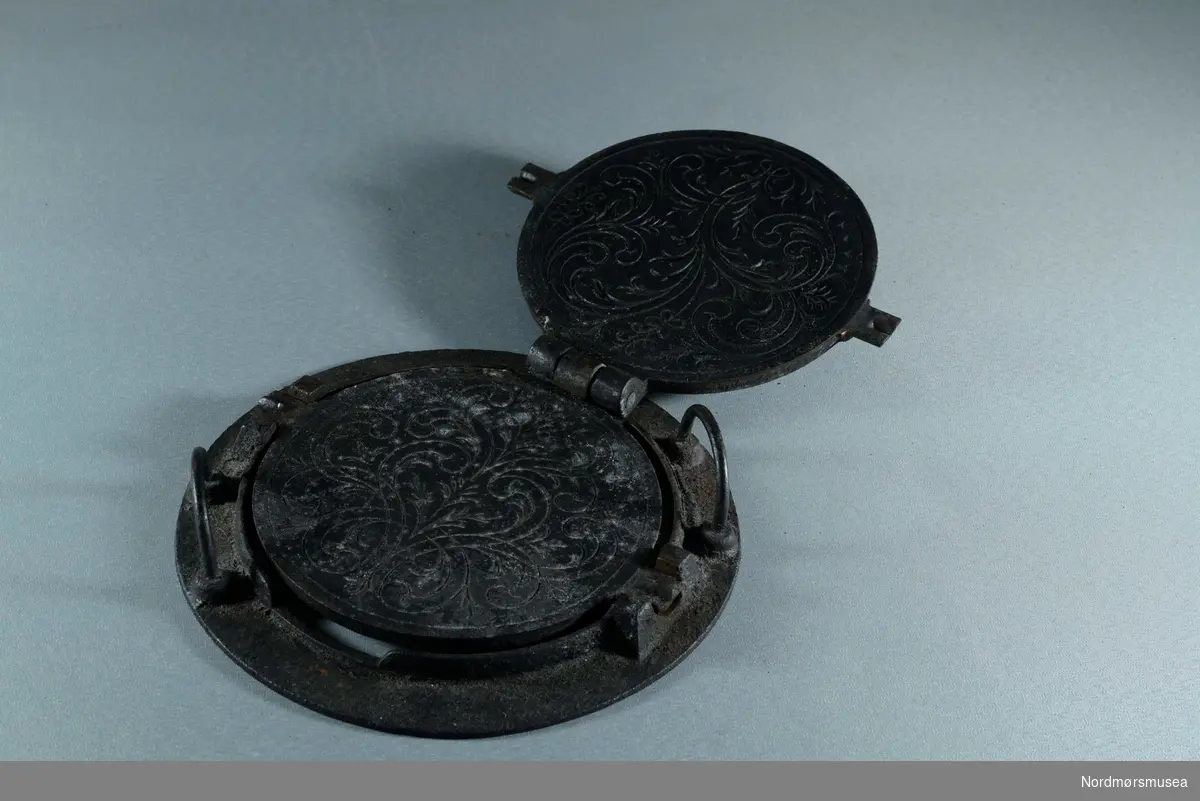 Rundt, to utstående sylinderformede tapper for å holde jernet på plass i ringen. ( MS.1608 b)
jernet består av to deler som er hengslet sammen.