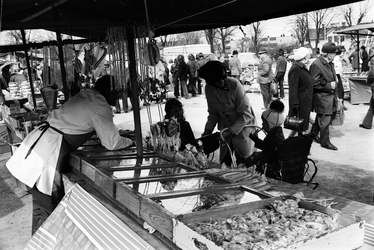 Kvinna och barn vid marknadsstånd med godis på vårmarknad