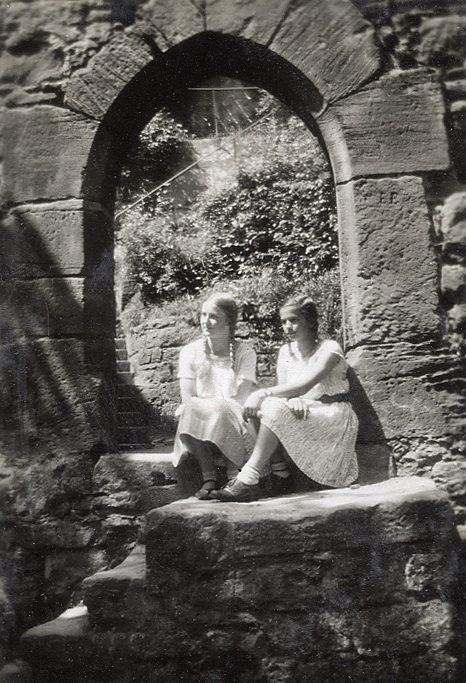 Två tonårsflickor i ljusa klänningar är fotograferade i en valvbåge.
Text under fotot: "Mädchen".