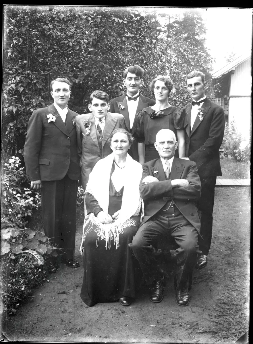 Familien Olufsen, foreldre og fem barn, 5 menn, 2 kvinner samlet ute i en hage foran et hus.