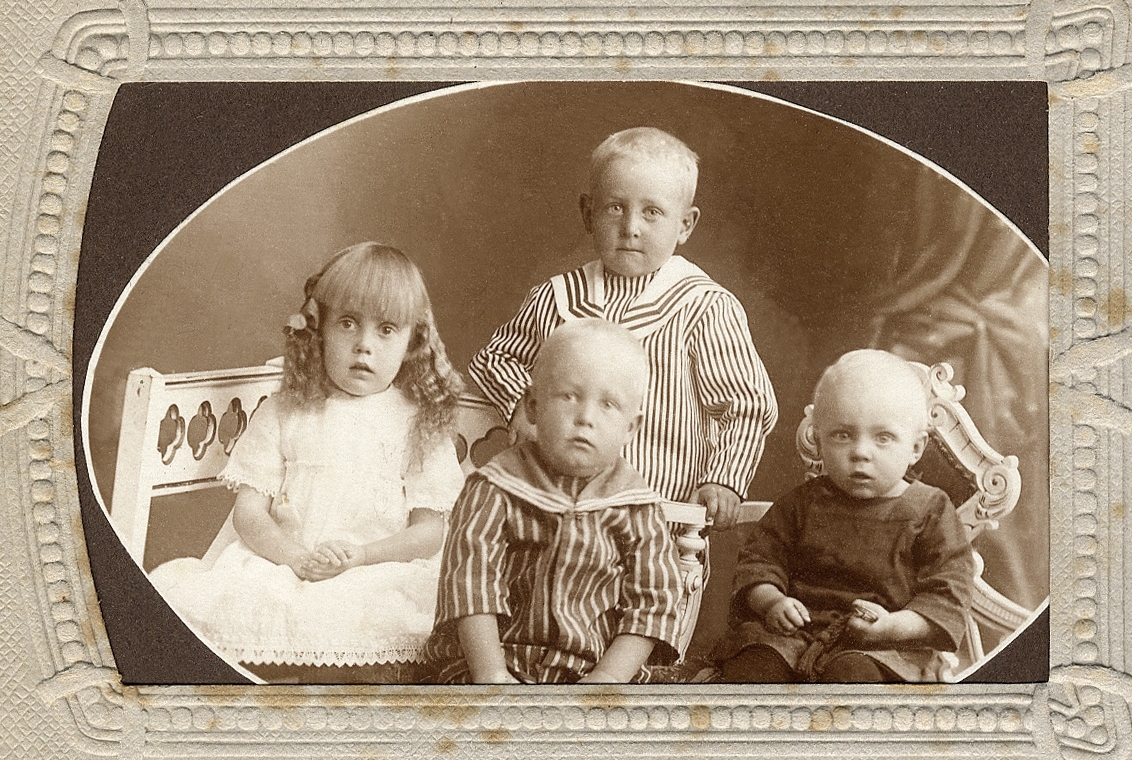 Några syskon: tre små pojkar och en flicka. 
Knäbild.