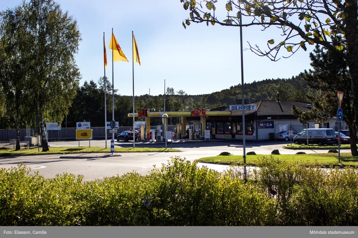 Vy över cirkulationsplats i Lindome centrum mot Bilhuset i Lindome AB/St1 med adress Smidesvägen 1 den 4 oktober 2016.  Bilverkstad och bensinstation. Vy mot sydost.