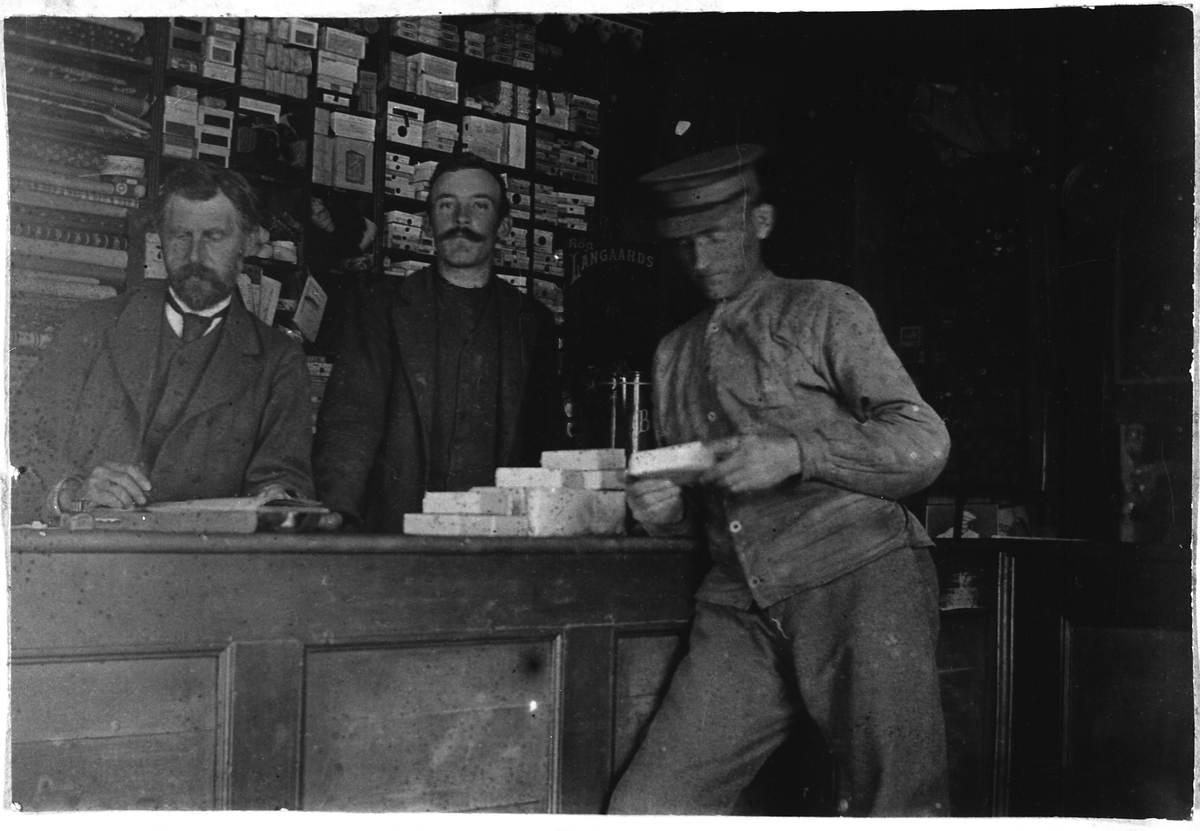Fra butikken til Johan Helmer Thune på Bøverbru ca. 1910. Thune med skjegg. Handelsbetjenten i midten er ukjent. Utafor disken Nils Håkenrud som var varekjører og gårdskar. Han kjørte ofte varer fra Kapp.