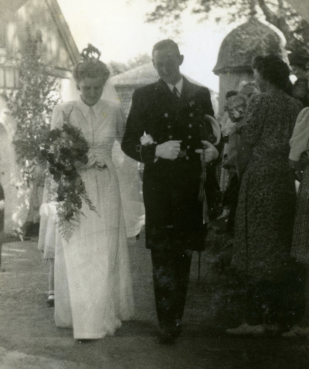 Bröllop mellan Nellie Gustafsson (1919 - 1993) och Eivind "Eje" Kullbring (1918 - 1996) som vigdes i Kållereds kyrka 1942-06-23. Paret vandrar på grusgången från kyrkan under tiden som det kastas ris på dem.